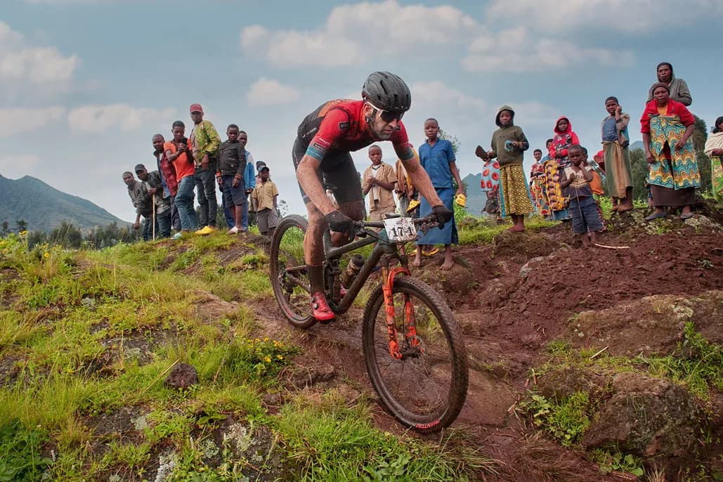 Cyclist riding through Rwanda’s mountain roads during road cycling tours in Rwanda, passing warm local communities and scenic highland landscapes.
