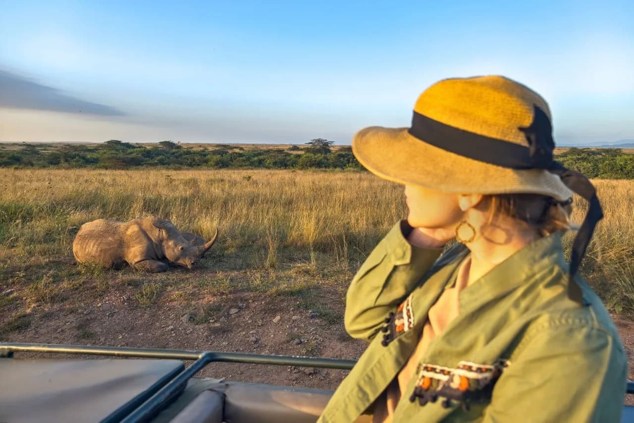 Girl traveler on safari in Serengeti National Park spotting a rhino during game drive adventure