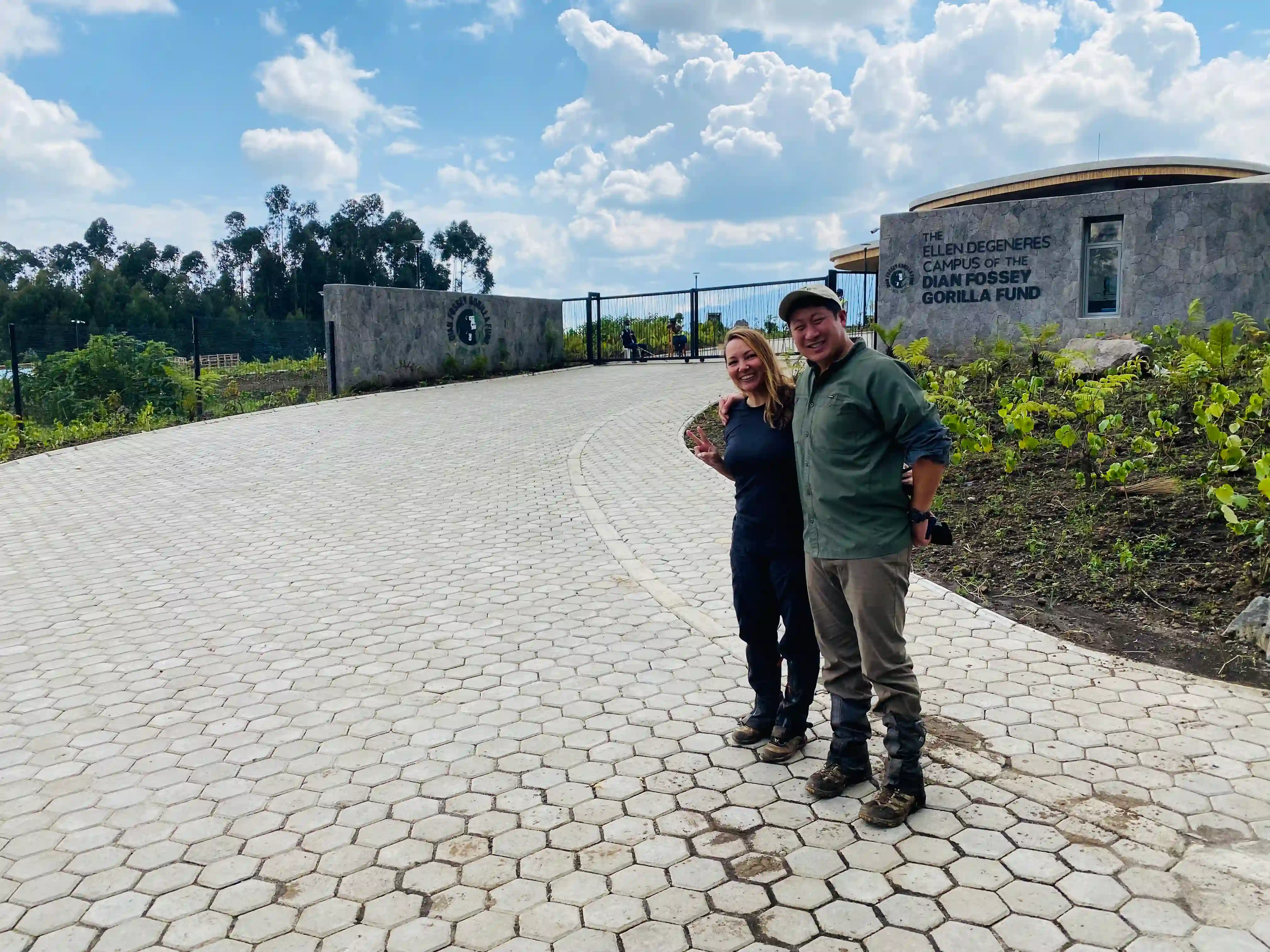 Couple embracing at the Dian Fossey Gorilla Fund Campus gate in Kinigi, Musanze Rwanda during a romantic Africa travel experience.
