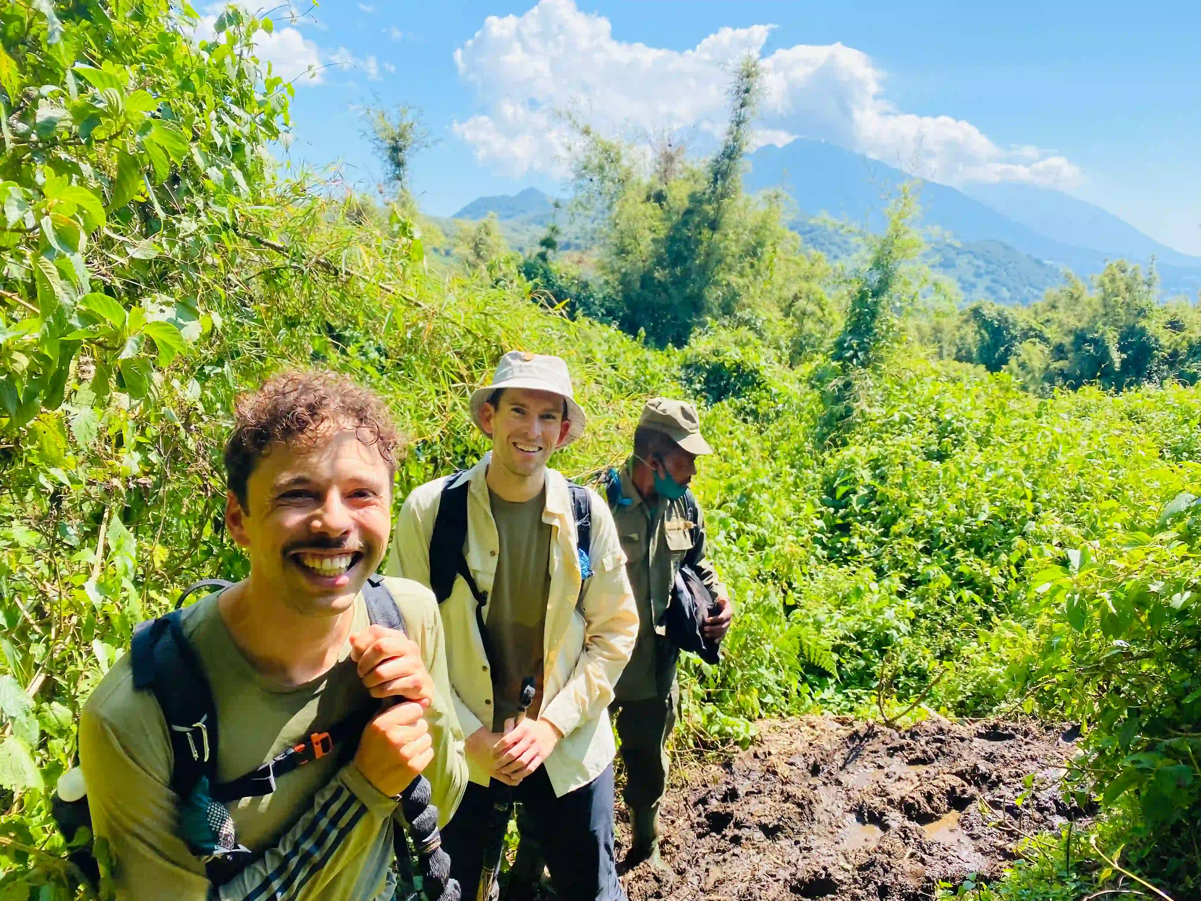 Travelers smiling in the lush volcanic landscapes of Rwanda, experiencing ecotours and impact in Rwanda through nature, wildlife, and community-based activities.