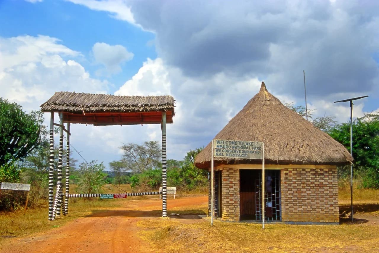 The gates of Lake Mburo National Park in Uganda stand as a welcoming entrance to one of East Africa’s most family-friendly safari destinations, perfectly representing Uganda Safaris for Families: Wildlife and Culture Tours. This image captures the iconic park entrance signage surrounded by open savannah, acacia trees, and the warm natural light typical of southwestern Uganda. Lake Mburo National Park is known for its calm landscapes, zebras, impalas, giraffes, and rich birdlife, making it ideal for families traveling with children. The gate symbolizes safety, conservation, and adventure, inviting families to explore Uganda’s wildlife at a gentle pace while also engaging with nearby pastoral communities and Ankole culture. It reflects a safari experience that blends education, cultural discovery, and responsible tourism, making Uganda safaris for families both meaningful and unforgettable.