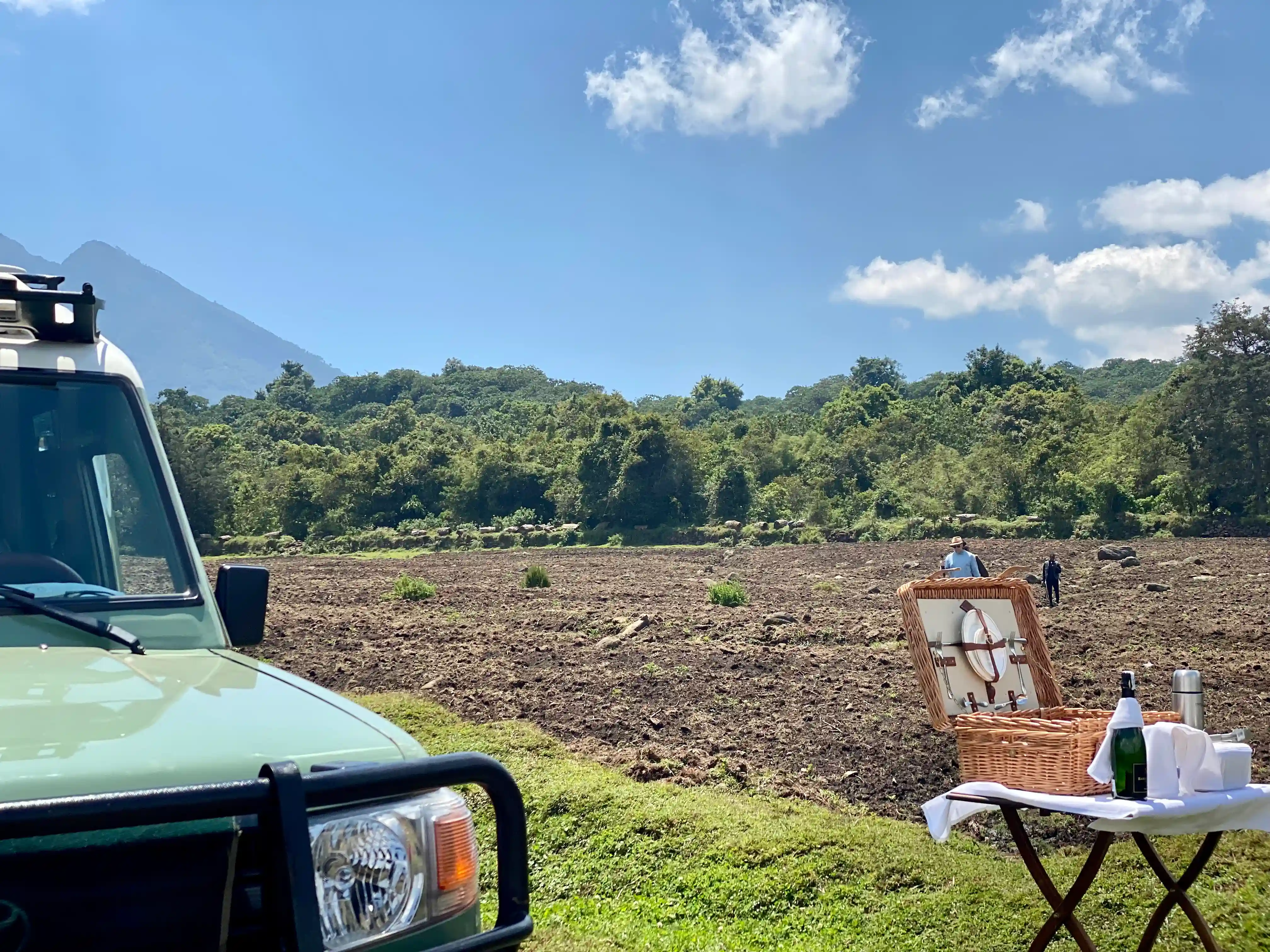 Luxury safari vehicle with wine setup on table awaiting guests returning from mountain gorilla trekking in Rwanda’s Volcanoes National Park.