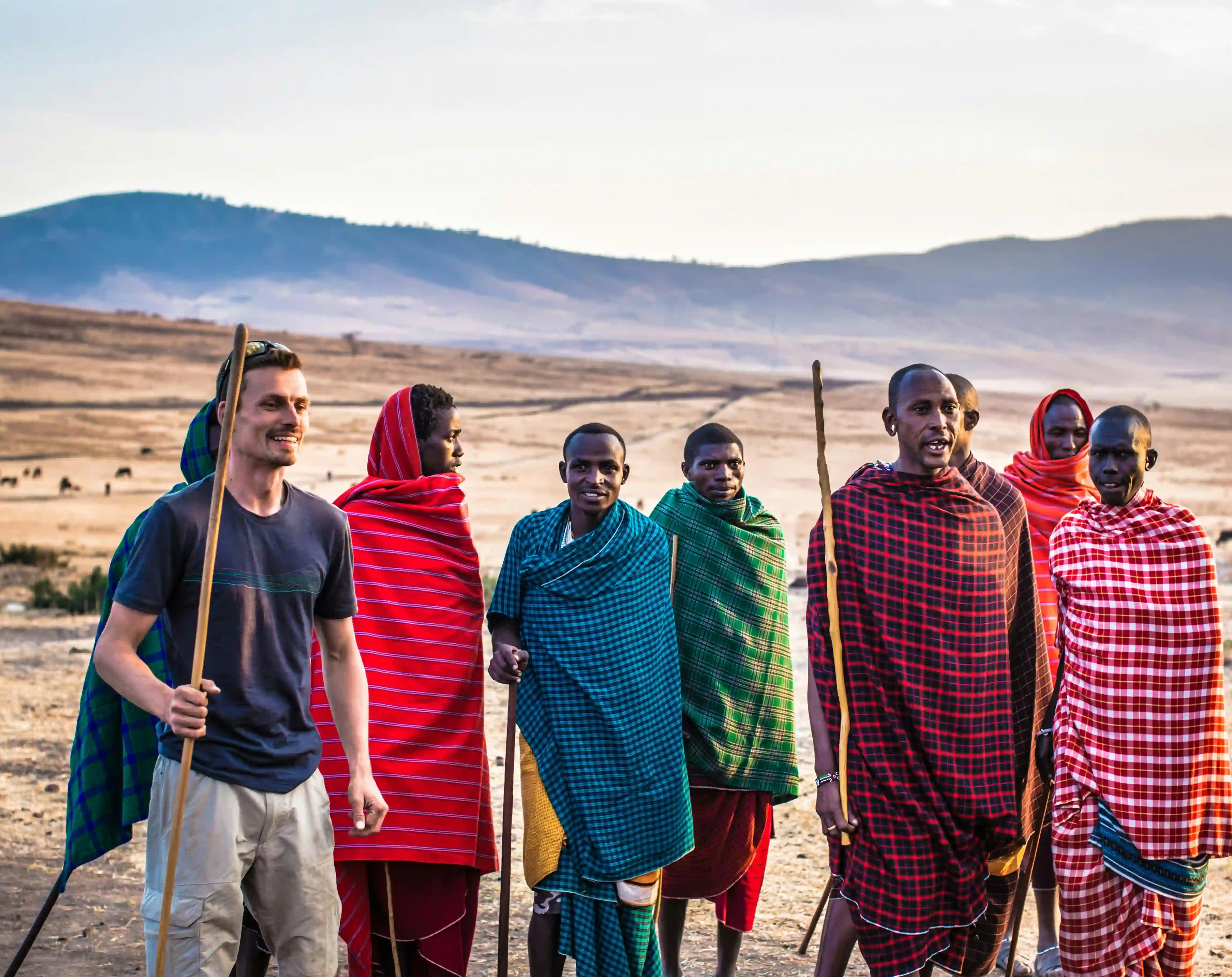 Maasai villagers and tourist singing and dancing together in a traditional Maasai village, experiencing local culture and community.