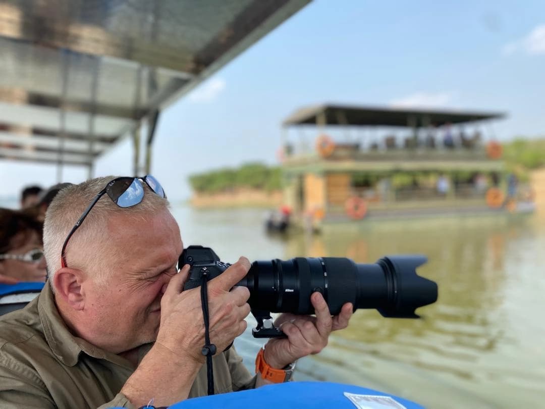 Traveler photographing stunning scenery during a boat cruise on the Nile River at Murchison Falls National Park, Uganda.
