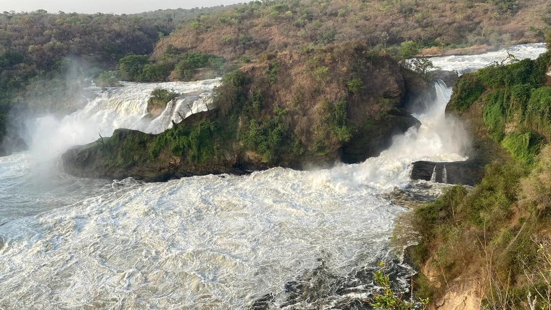 Murchison Falls National Park in Uganda, seen from a distance as the Nile River narrows and crashes through the gorge, showcasing one of Africa’s most powerful waterfalls