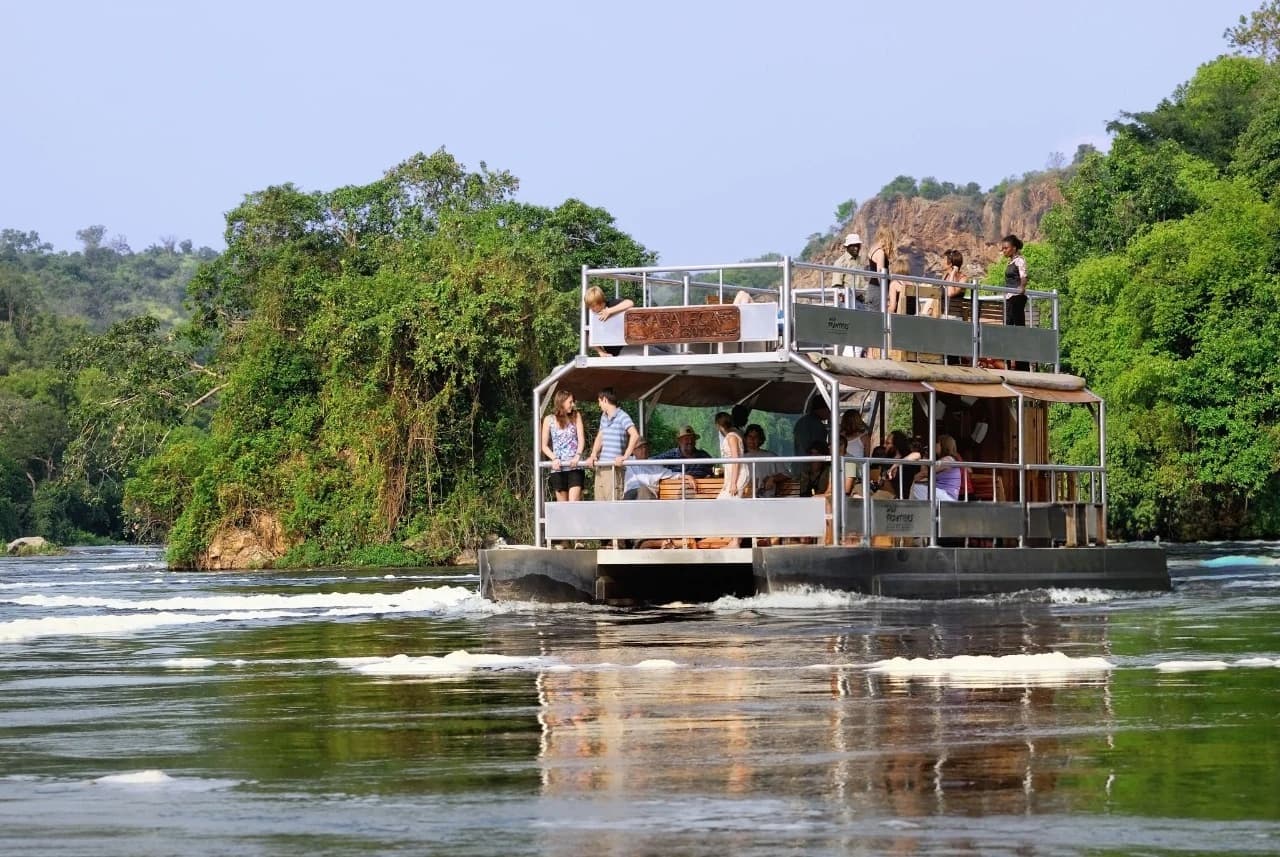 Travelers enjoying a boat cruise along the Nile at Murchison Falls with a local guide , comparing Queen Elizabeth vs Murchison Falls Safaris.
