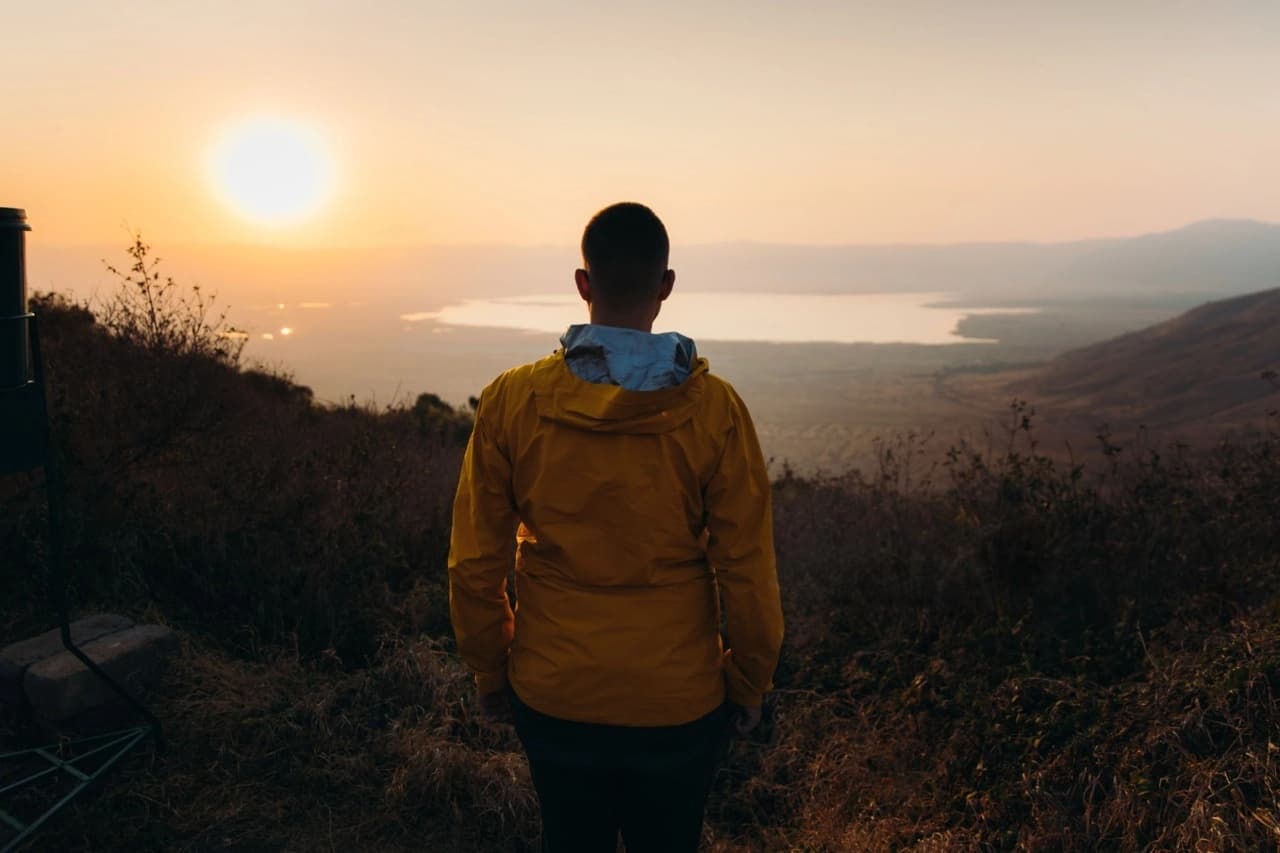 Traveler standing at the rim of Ngorongoro Crater Lake in Tanzania, overlooking the vast landscape during a safari adventure