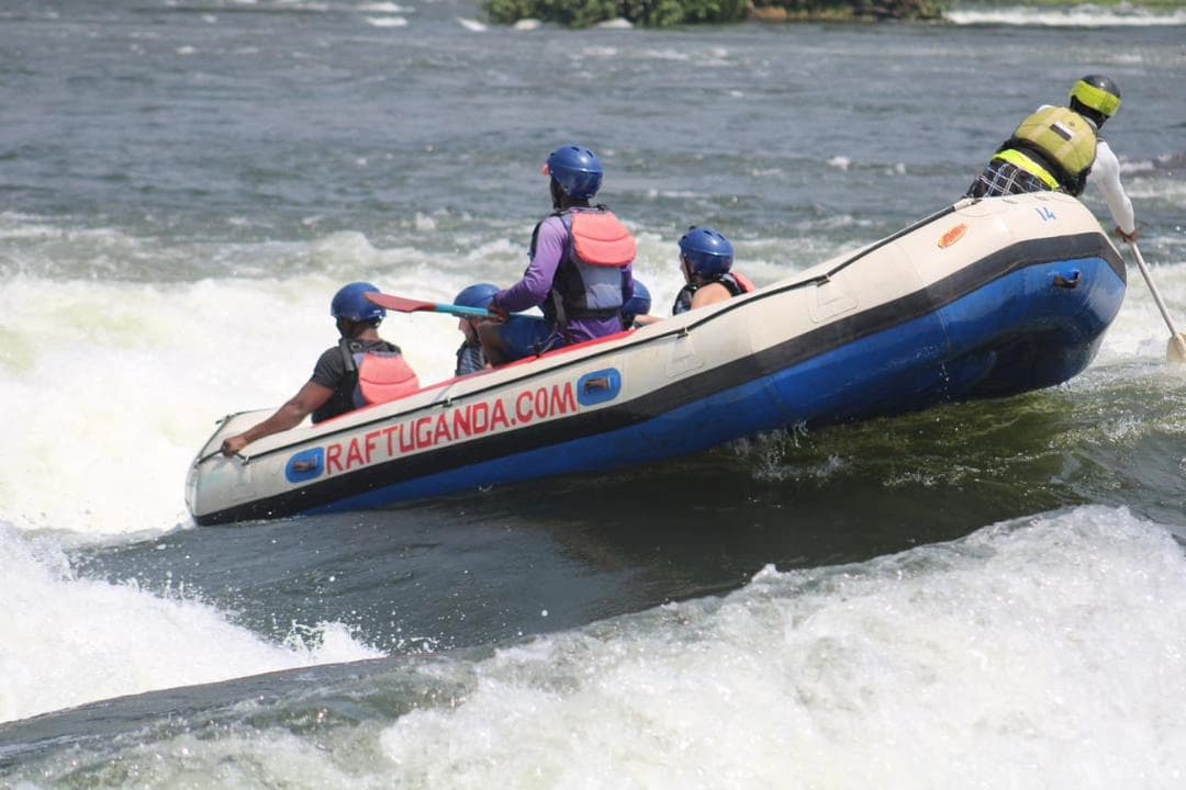 Adventure travelers rafting on the River Nile in Uganda, experiencing thrilling white-water rapids surrounded by lush African scenery.