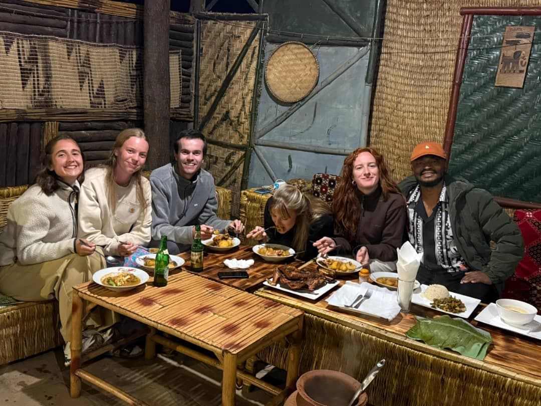 Group of travelers enjoying a traditional Rwandan dinner with a local guide — How to Experience Rwanda Like a Local cultural dining experience.
