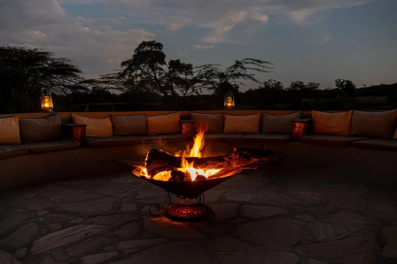 A glowing campfire surrounded by warm lantern light at a South African eco-lodge, illustrating how to plan South Africa eco luxury safari with sustainable, nature-immersive experiences.