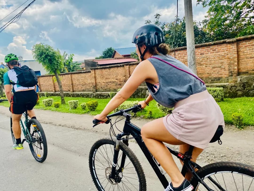 Cyclist biking through Musanze village roads with volcanic peaks in the background – road cycling tours in Rwanda.