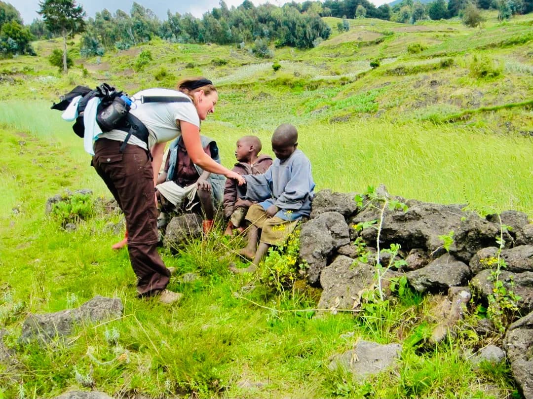 A solo female traveler greeting smiling local children on a village path, sharing warmth, connection, and authentic cultural exchange in Africa