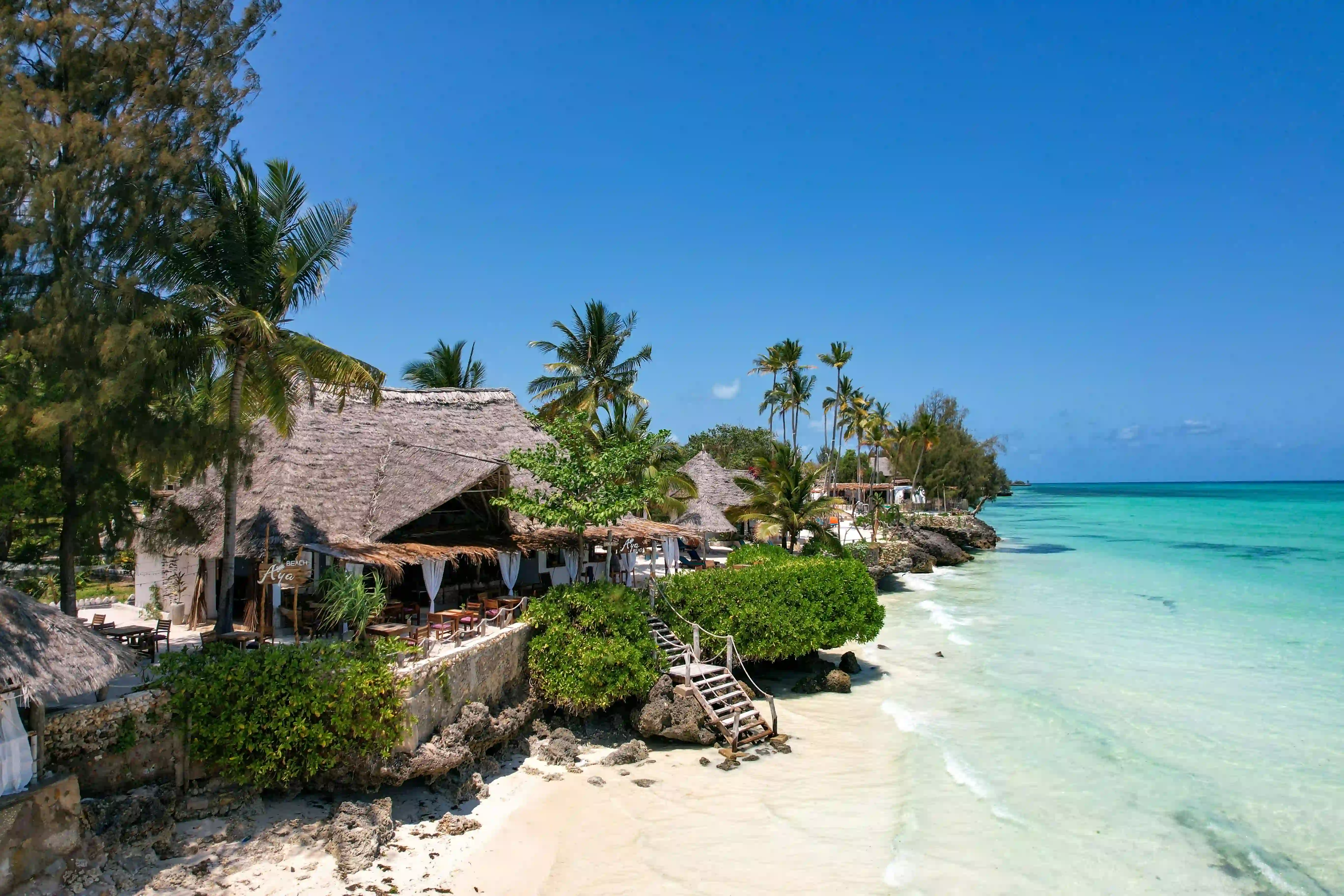 Zanzibar beach at sunset with calm turquoise waves and soft white sand, showcasing the relaxing side of the Best family friendly safari and tours in Tanzania.